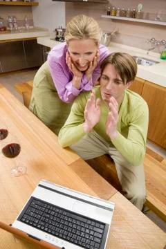 Young couple in kitchen, using laptop, portrait Stock-Fotos