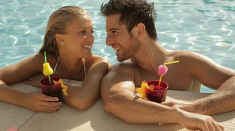 Young couple laughing with drinks at side of pool Video stock 43624333