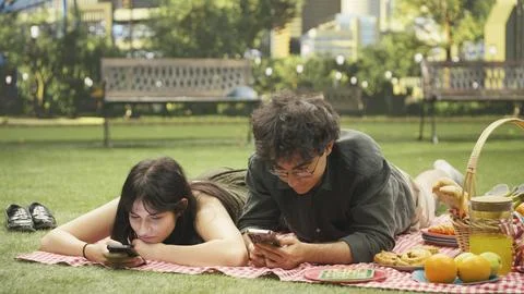 Young couple laying side by side illustrating phubbing and phone addiction Stock Photos