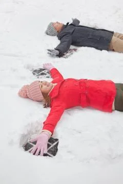 Young couple laying in snow making snow angels Stock Photos