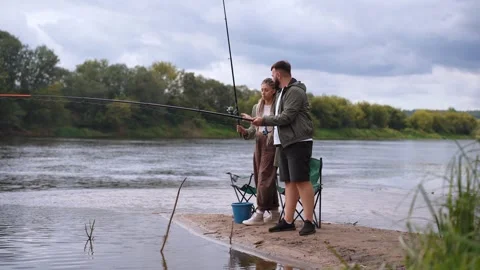 Young couple learning to fish together on a river bank Stock Footage 327531489