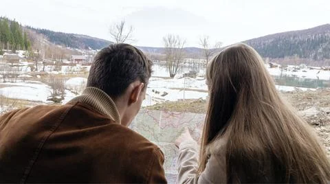 A young couple learns a roadmap while discussing a road trip route Stock Photos