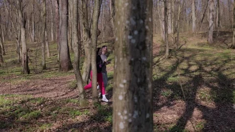 Young couple in light athletic clothing runs along bright sunlit forest path Video stock 335543377