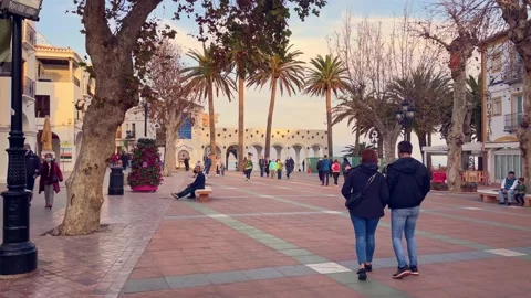 Young couple lightly kissing while crossing the Plaza at Balcon de Europa. Stock Footage 238076080