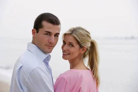 Young couple looking back, on beach Stock Photos