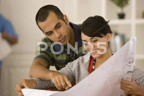 Young couple looking at blueprints in new house Stock Photos