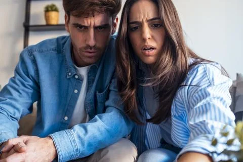 Young couple looking down with stunned and surprised expressions, feeling s.. Stock-Fotos