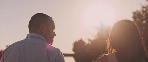 Young couple looking at each other with love, smiling, while walking at sunse Stock Footage 136242508