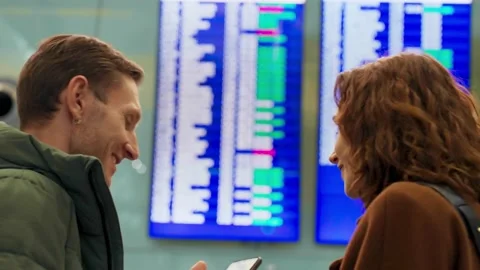 Young couple looking at flight schedule at airport. Pair checking airline Stock Footage 169603751