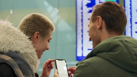 Young couple looking at flight schedule at airport. Pair checking airline Stock Footage 169823142