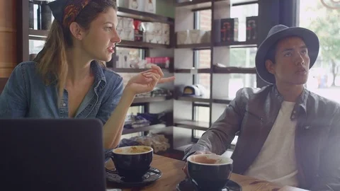 A young couple looking a laptop in a coffee shop Stock Footage