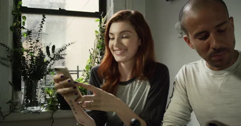 Young couple looking at the mobile phone and talking while having breakfast Vídeo Stock 63374738