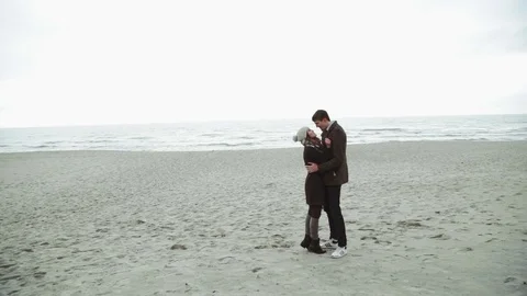 Young couple looking at the sea, walking the beach, coat and hat, Baltic or Stock Footage 73874352