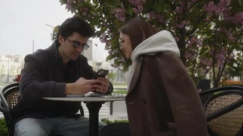 Young couple looking at smartphone together at outdoor cafe Video stock 335003531
