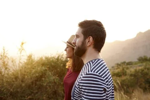 Young couple looking at something surrounded by bushes and very bright sun to Stock Photos