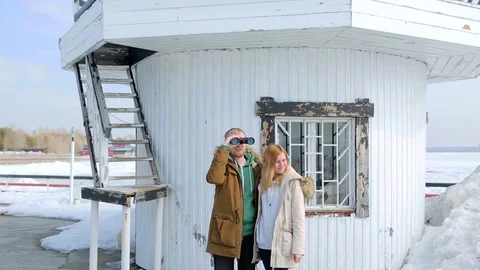 Young couple looking through binoculars in the background of the lighthouse 스톡 동영상 74895610