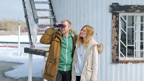Young couple looking through binoculars in the background of the lighthouse Видео 74895812