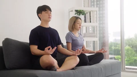 Young couple in lotus pose practicing Yoga together at home. Video stock 248593243