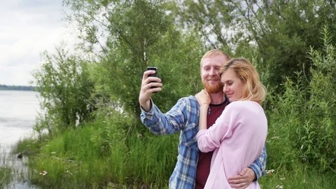 Young couple in love on the background of the river take a selfie on the phone Stock Footage 106964898