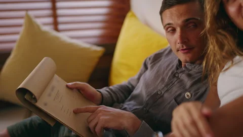 Young couple in love looking at menu, choosing dessert in hipster tropical cafe Stock Footage 265397346