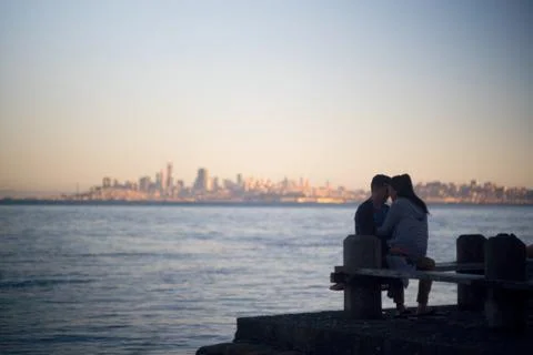 Young Couple in Love by Ocean with City Skyline in Background Stock Photos