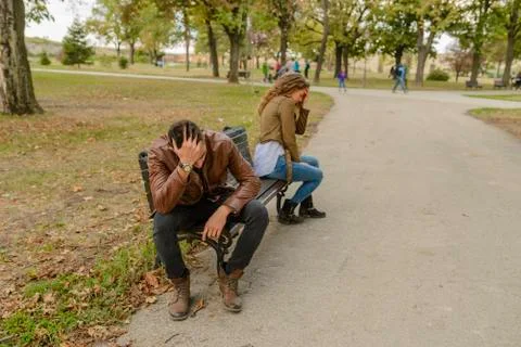 Young couple with the love problems sitting in the city park Foto stock