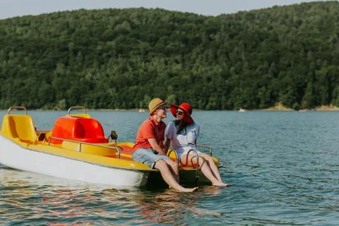 Young couple in love talking while pedal boating on the lake. Stock Photos