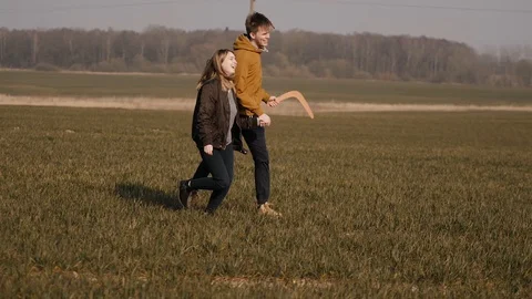 Young couple in love together launch a boomerang in a field Stock Footage 129010195