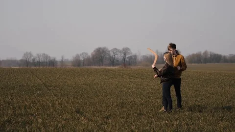 Young couple in love together launch a boomerang in a field Stock Footage 129010462