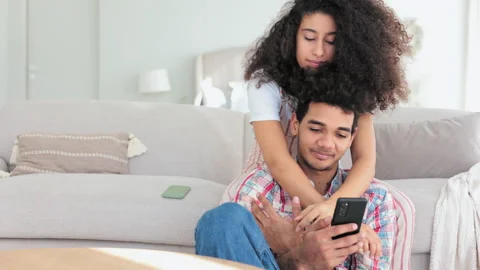 Young couple in love is using device and hugging on sofa in apartment room spbi. Stock Footage 197777979