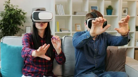 Young couple in love using vr headset for playing the videogame while sitting on Stock Footage 76246269