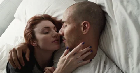 Young couple lying on a bed and kissing Stock Footage 63374322