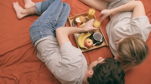 Young couple is lying in bed and having a healthy breakfast. Stock Footage 74076085