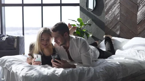 Young couple lying on bed and scrolling through photos on their phone. Stock-Footage 267221769