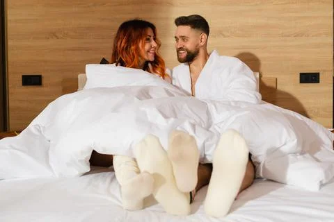 Young couple lying in bed dressed in bathrobes. Stock Photos
