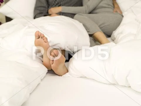 Young couple lying in bed, low section,close-up of feet Stock Photos