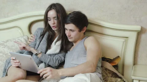 Young couple lying on the bed make shopping over the Internet using tablet Video stock 61001990