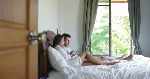 Young Couple Lying In Bed Use Tablet Computer Talking Chatting Online, Beautiful Stock Footage