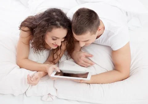 Young couple lying on the bed using tablet pc Stock Photos