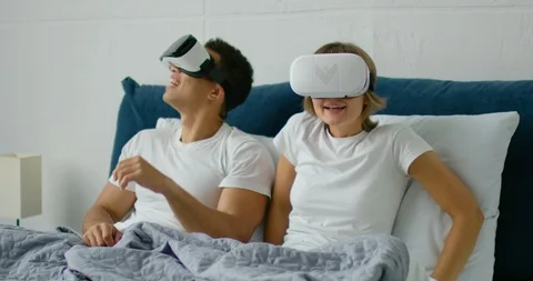 Young couple lying in bed, watching 360 video in virtual reality headsets Stock Footage 113295491