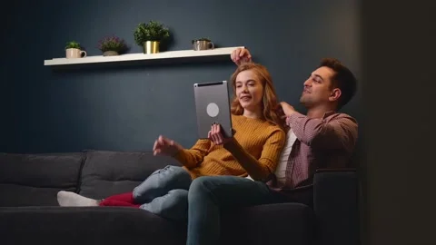 Young couple lying on a couch relaxing and embracing while watching something on Stock Footage 147478654