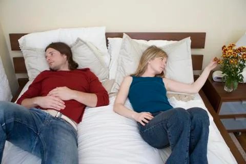 A young couple lying down on a bed Stock Photos