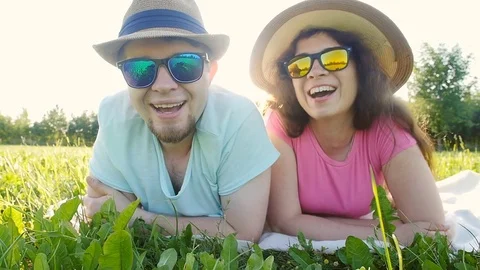 Young couple lying down in grass and smiling Stock Footage 77024279
