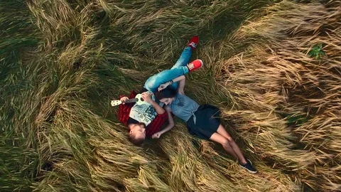 Young couple lying in a field at sunset Stock Footage 78727595