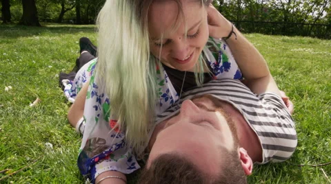 Young couple lying on the grass and kissing in a city park Stock Footage 58581602