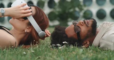 Young couple lying on the grass and playing with vr glasses Stock Footage 201134449