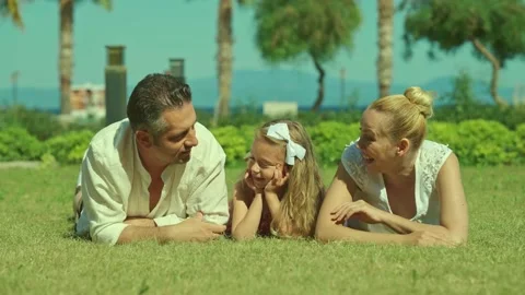 Young couple is lying on the grass in the sun with their young daughter. Stock Footage 165998488