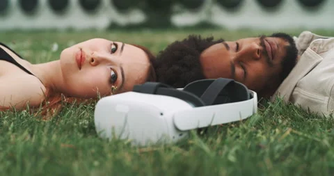 A young couple lying on the grass with virtual reality glasses Stock Footage 201114594
