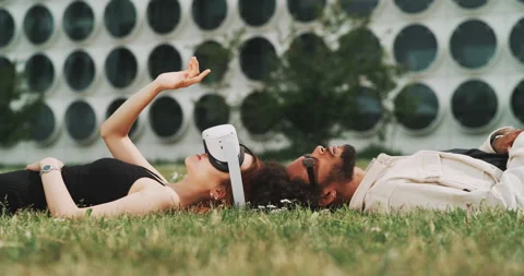 A young couple lying on the grass while playing with vr glasses Stock Footage 201116966
