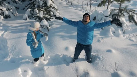 Young couple lying on snow and making snow angels in pine forest Stock Footage 86570852